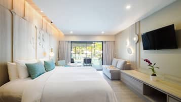 A modern hotel room with a large bed, a sofa, a TV, and a balcony with outdoor seating.