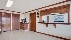 A spacious kitchen with wooden cabinets, a countertop, and a clock on the wall. - Super 8 by Wyndham Oklahoma/Frontier City (Oklahoma City)