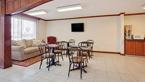 A dining area with a wooden staircase, a sofa, and a television on the wall. - Super 8 by Wyndham Oklahoma/Frontier City (Oklahoma City)
