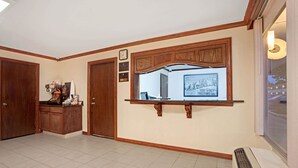 A spacious room with a large window, a built-in shelf, and a wall-mounted clock. - Super 8 by Wyndham Oklahoma/Frontier City (Oklahoma City)