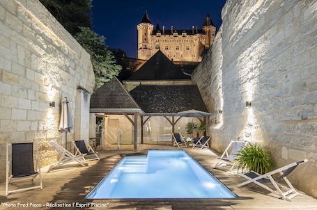Una piscina al aire libre, sombrillas, sillones reclinables de piscina