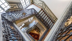 Una gran escalera con barandillas de metal negro ornamentado y un suelo con diseño.