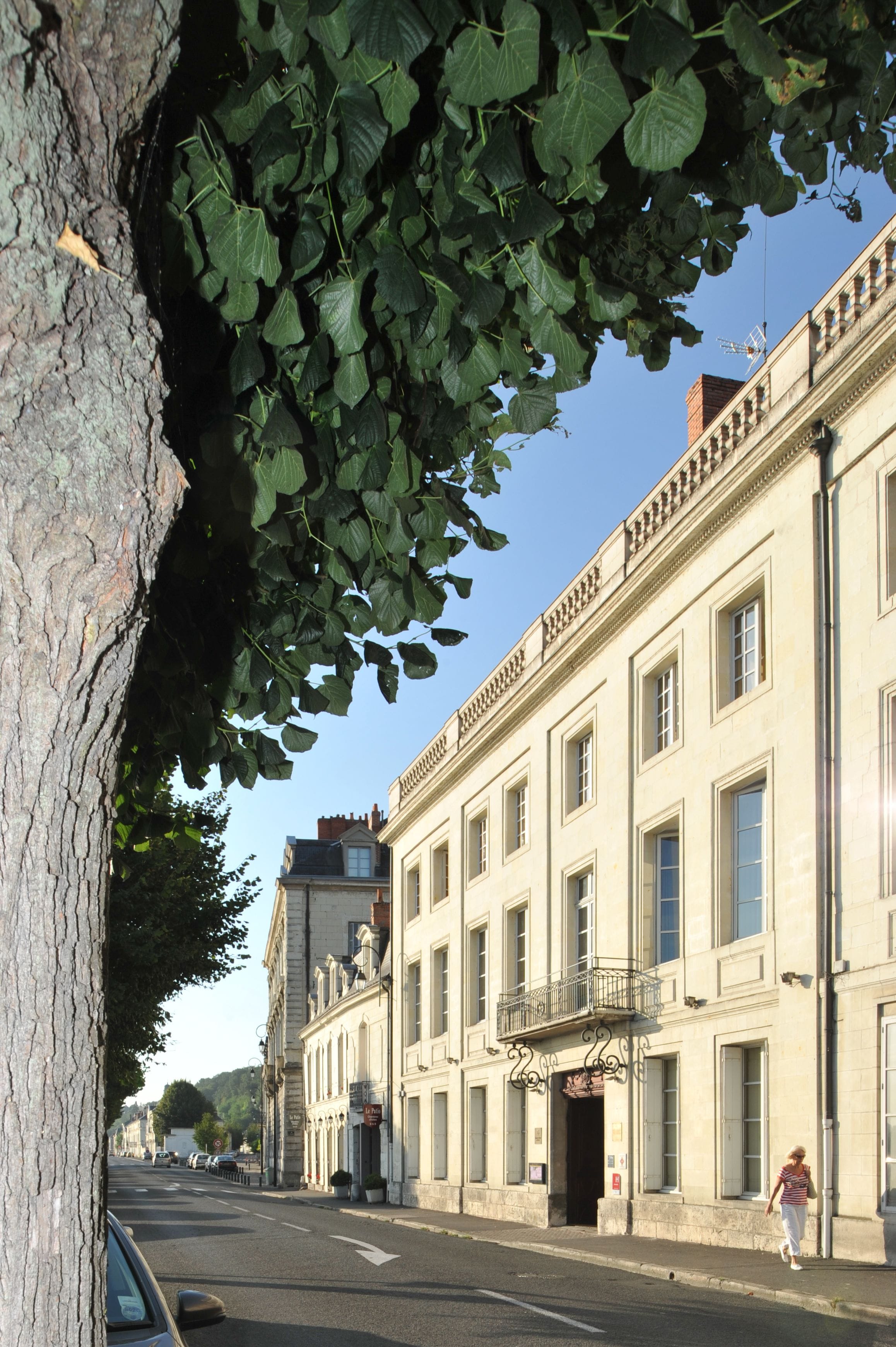 A street with a building featuring a balcony and large windows.
