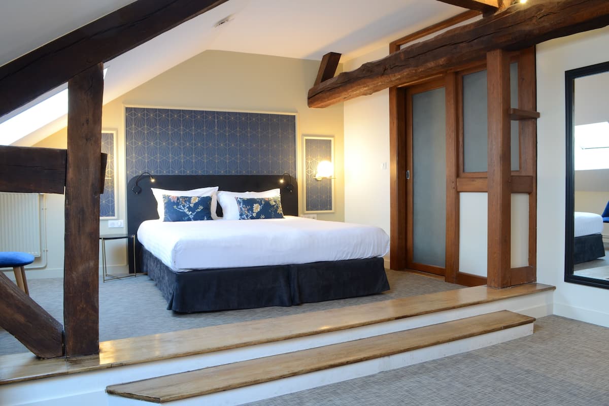 A bedroom with a bed, a nightstand, and a window.