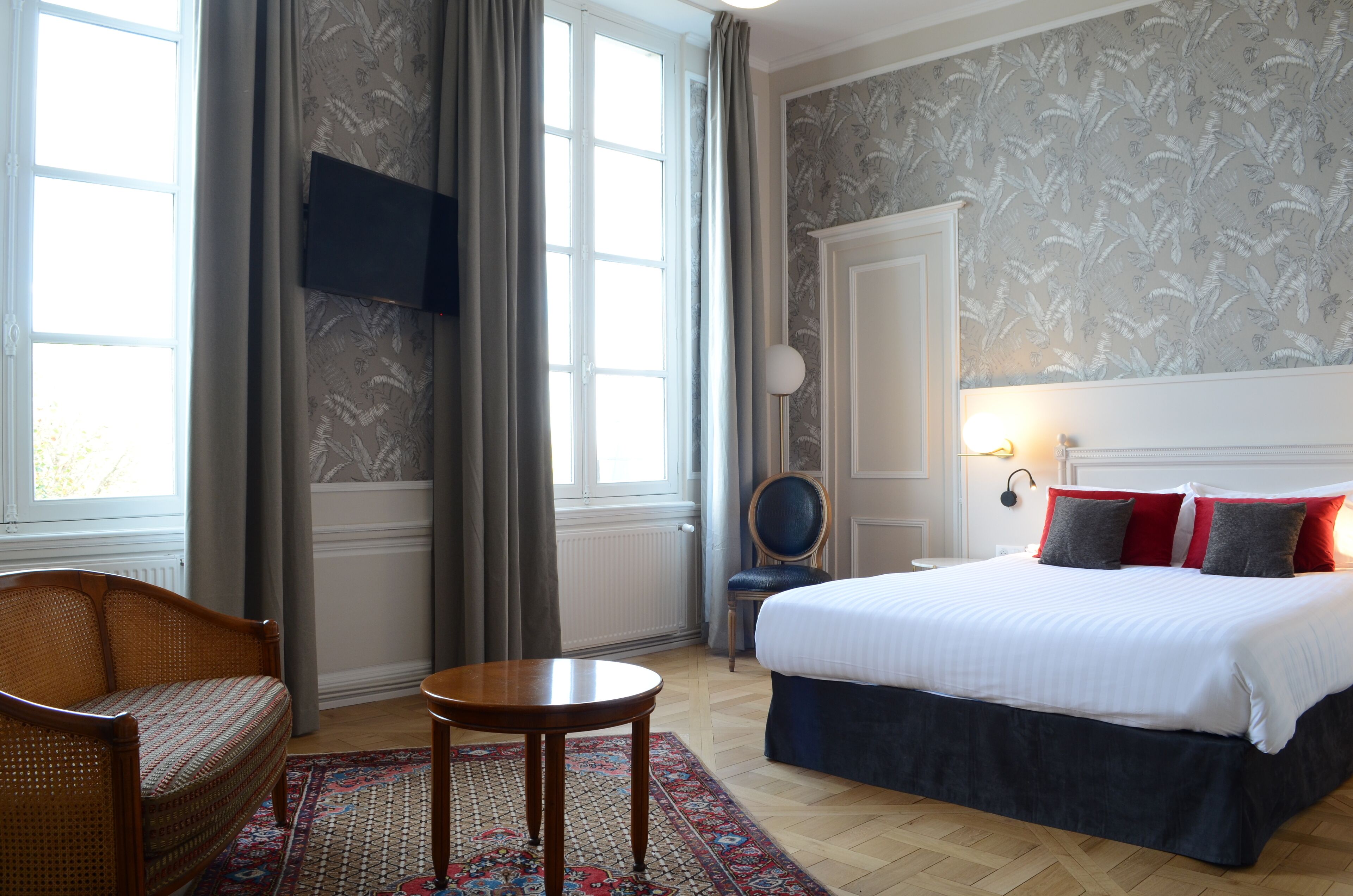 Una habitación de hotel con cama, una silla, una mesa y un ventanal grande.