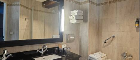 Un baño con dos lavamanos, un espejo grande, una bañera y toallas.