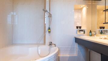 A modern bathroom with a freestanding bathtub, a handheld showerhead, and a vanity with a mirror.