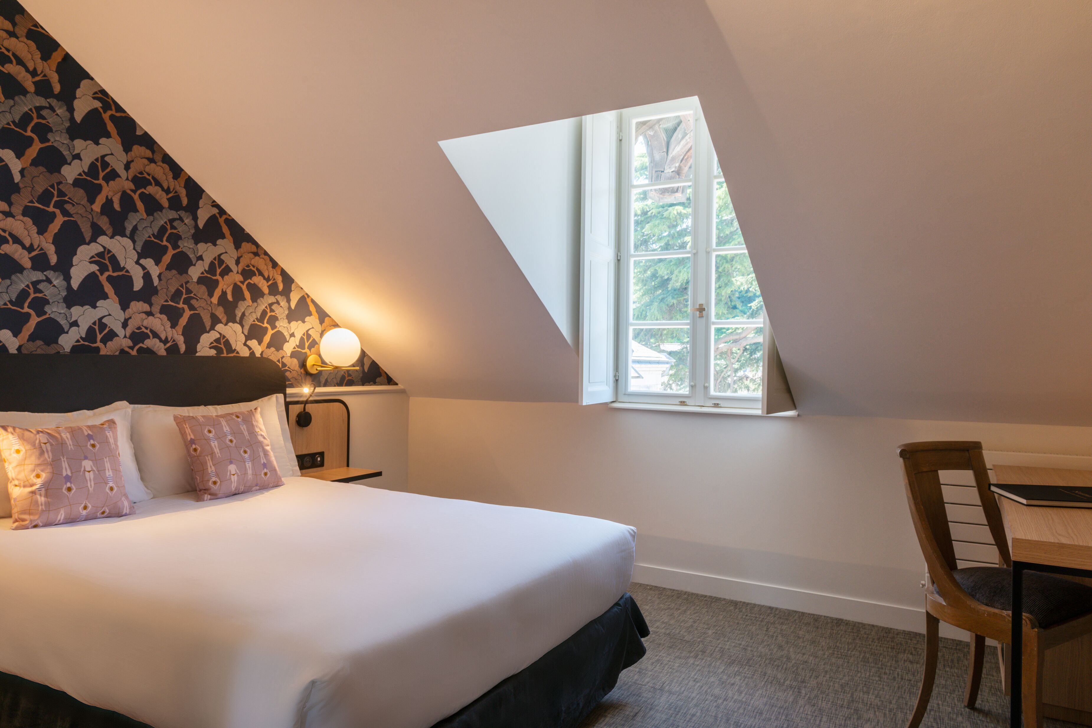 Een slaapkamer met een bed, nachtkastje, bureau en raam.
