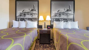 A hotel room with two beds, each with a patterned bedspread, a nightstand with a lamp, and two framed pictures on the wall.