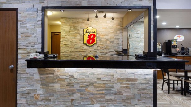 A reception area with a stone wall and a 'Super 8' sign. - Super 8 by Wyndham Decorah (Decorah)