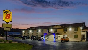 A motel with a Super 8 sign, multiple parking spaces, and a well-lit entrance. - Super 8 by Wyndham Decorah (Decorah)