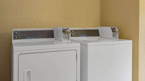 Two commercial dryers side by side in a laundry room with beige walls. - Super 8 by Wyndham Decorah (Decorah)