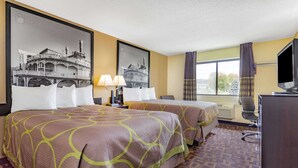 A hotel room with two beds, a desk with a television, and large framed pictures on the walls. - Super 8 by Wyndham Decorah (Decorah)