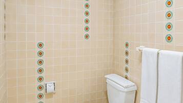 Casa de banho com sanita, um porta-toalhas com duas toalhas e azulejos decorativos nas paredes.