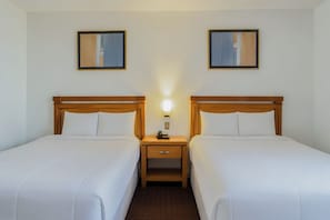 A hotel room with two single beds, a nightstand with a lamp, and two framed pictures on the wall. - Hotel San Jorge (Saltillo)