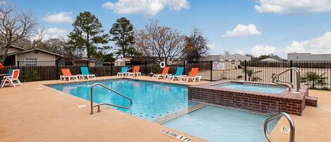 A swimming pool with lounge chairs and a brick deck.