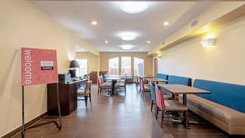 A spacious dining area with a 'Welcome' sign, tables, benches, and a reception desk.