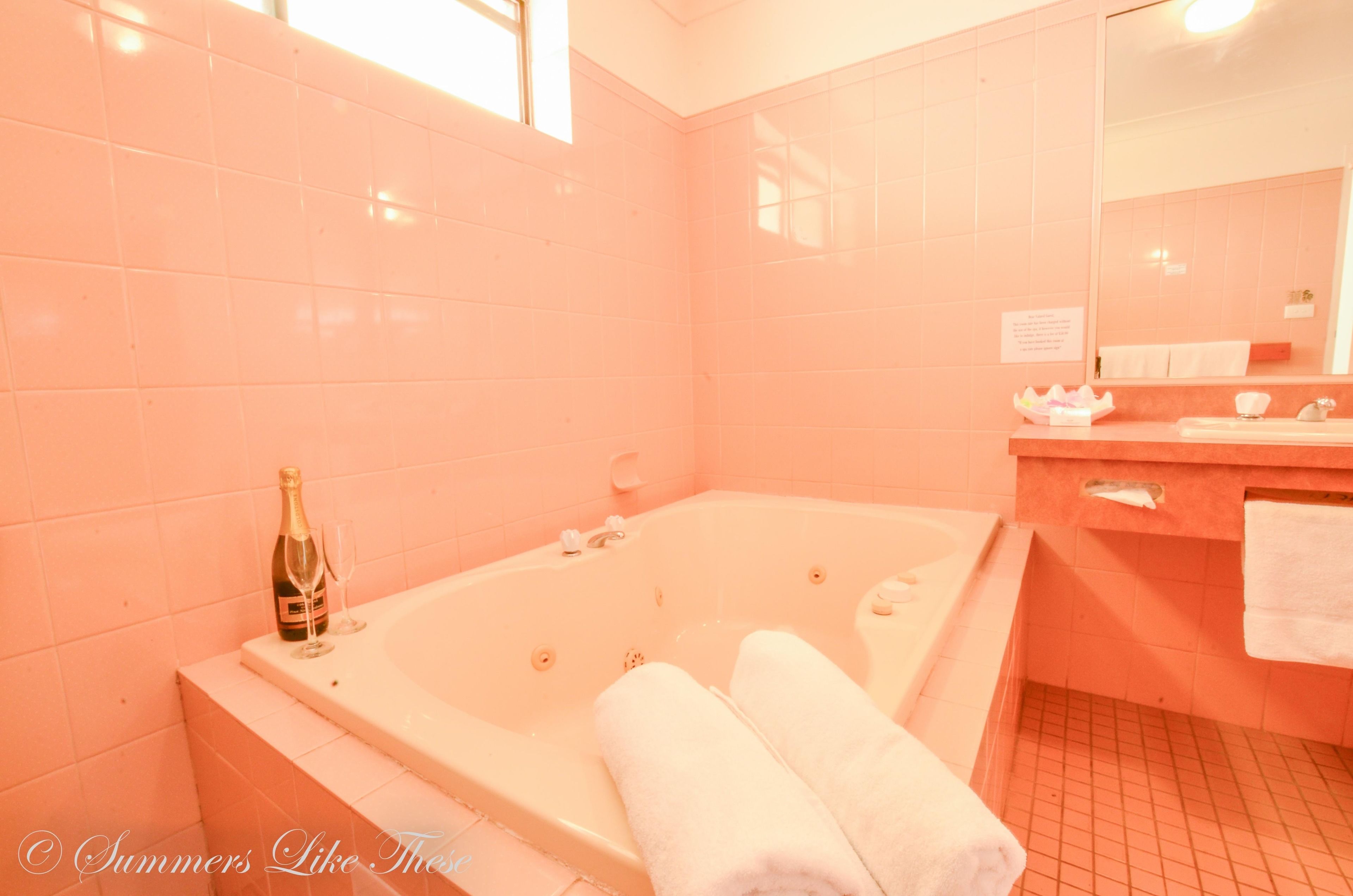 A bathroom with a large bathtub, a bottle of champagne, and a glass on the counter.