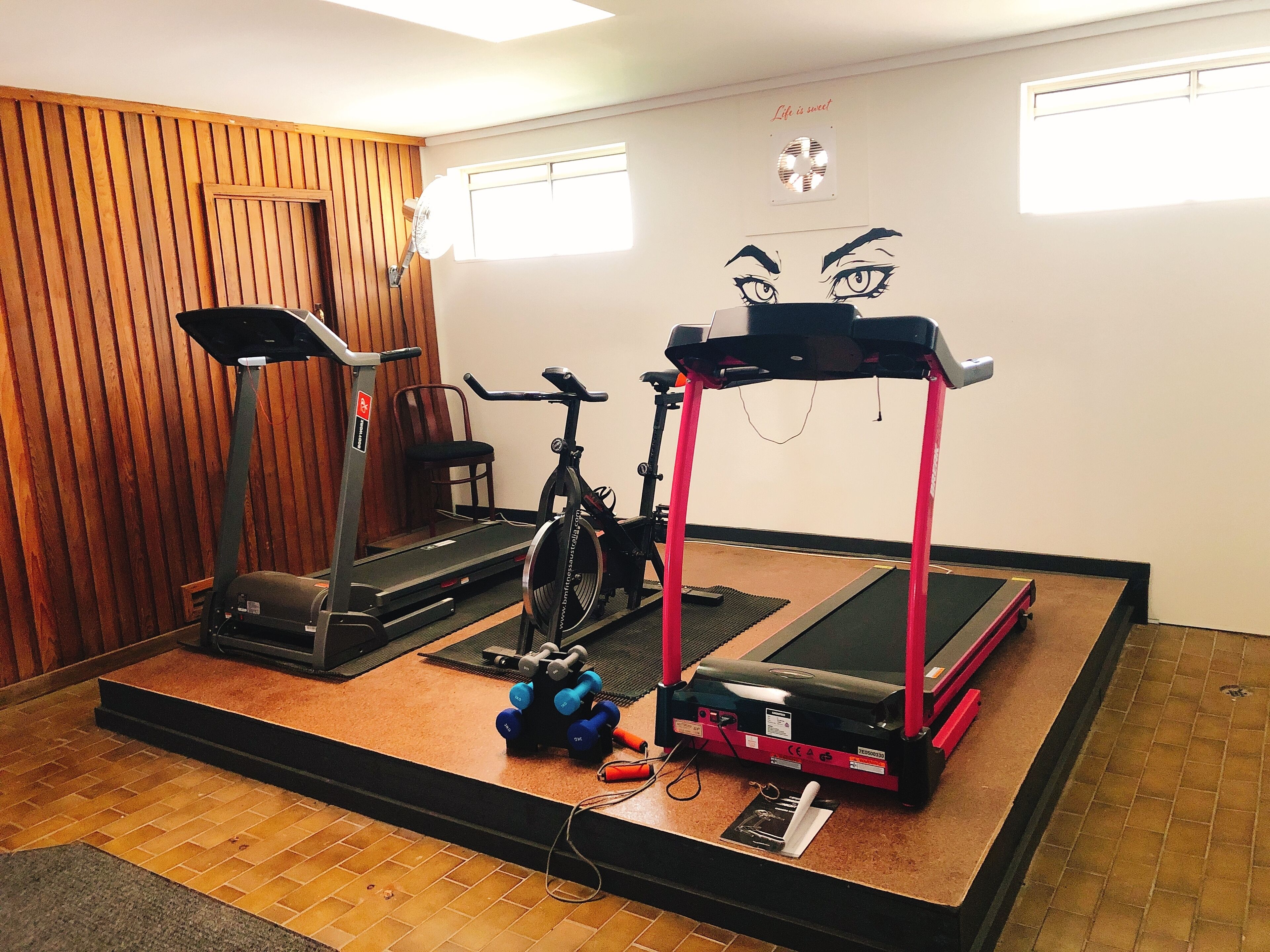 Un gimnasio en casa con cinta de correr, bicicleta estática y elíptica.
