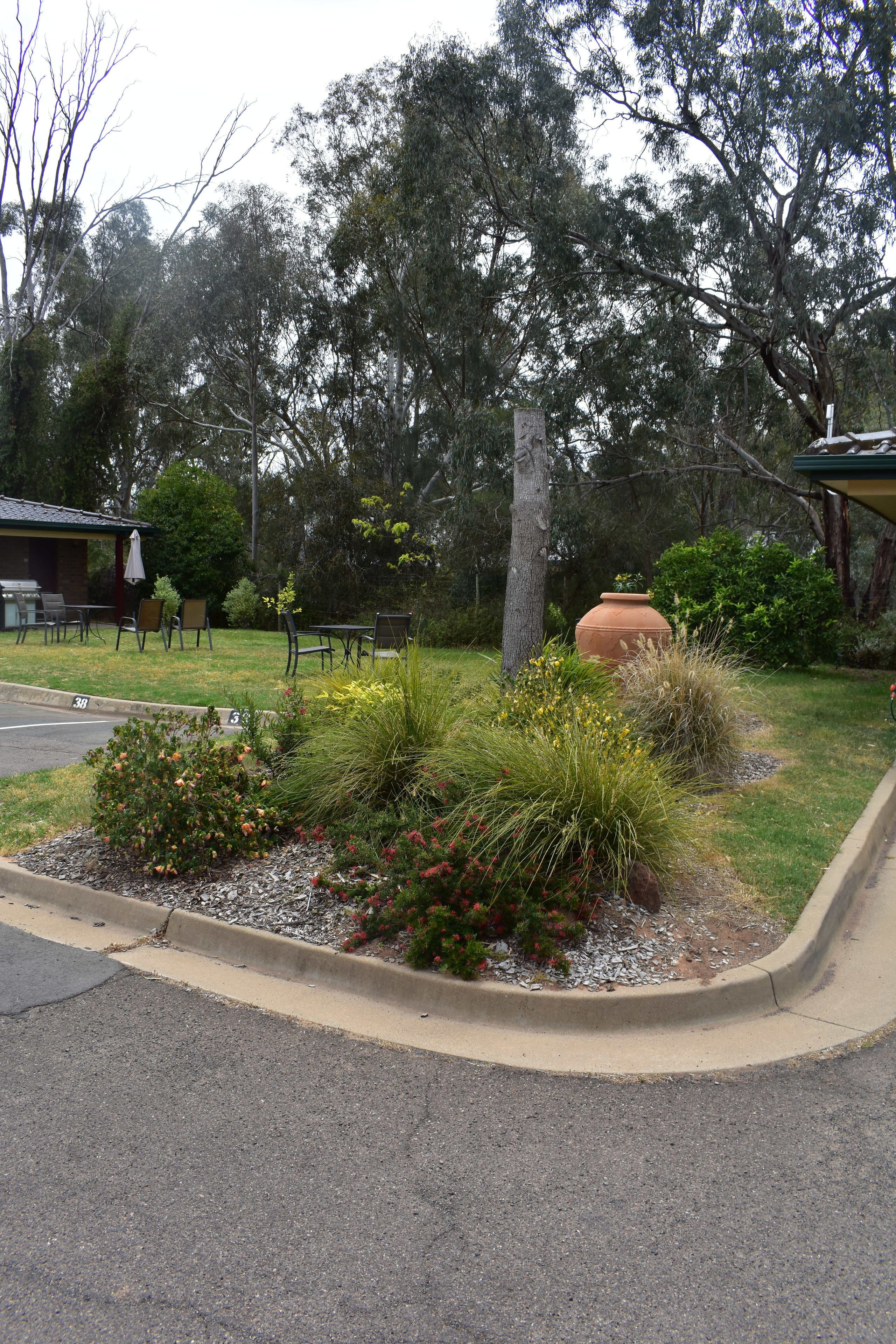 Un jardí paisatjistic amb zona de terrassa, mobiliari exterior i una gran jardiniera.