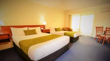 A hotel room with two beds, a desk, a chair, and a large window.