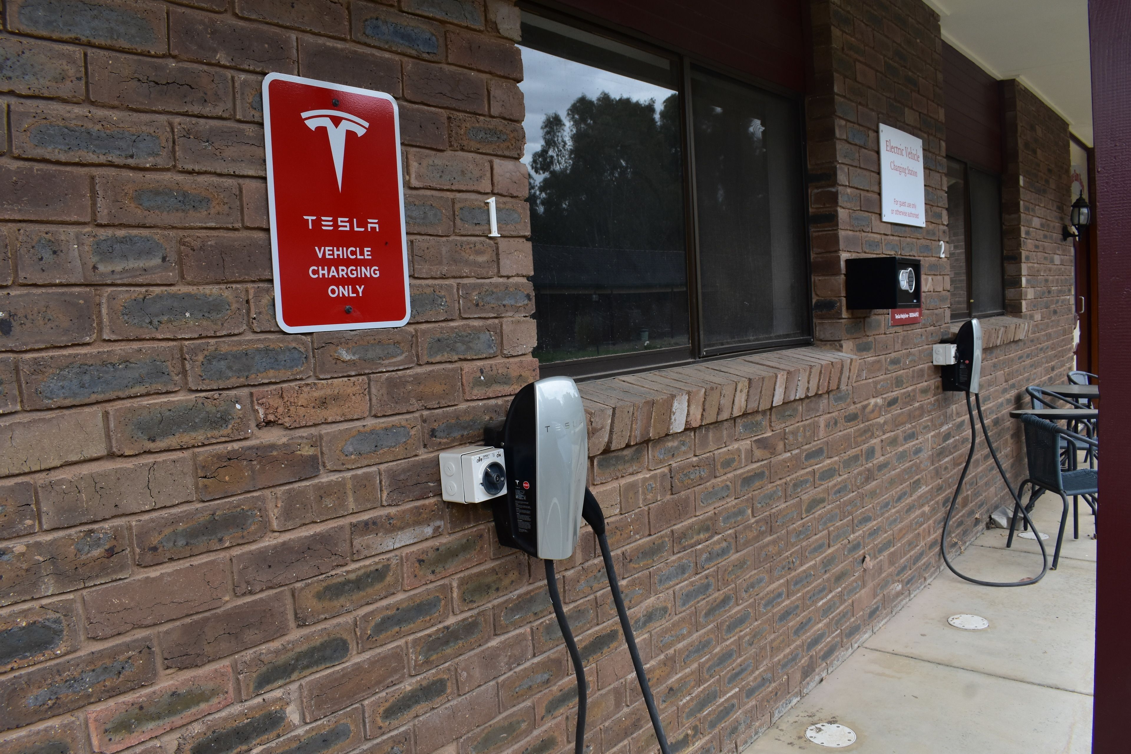 Un bâtiment en briques doté d’une borne de recharge pour véhicules Tesla.