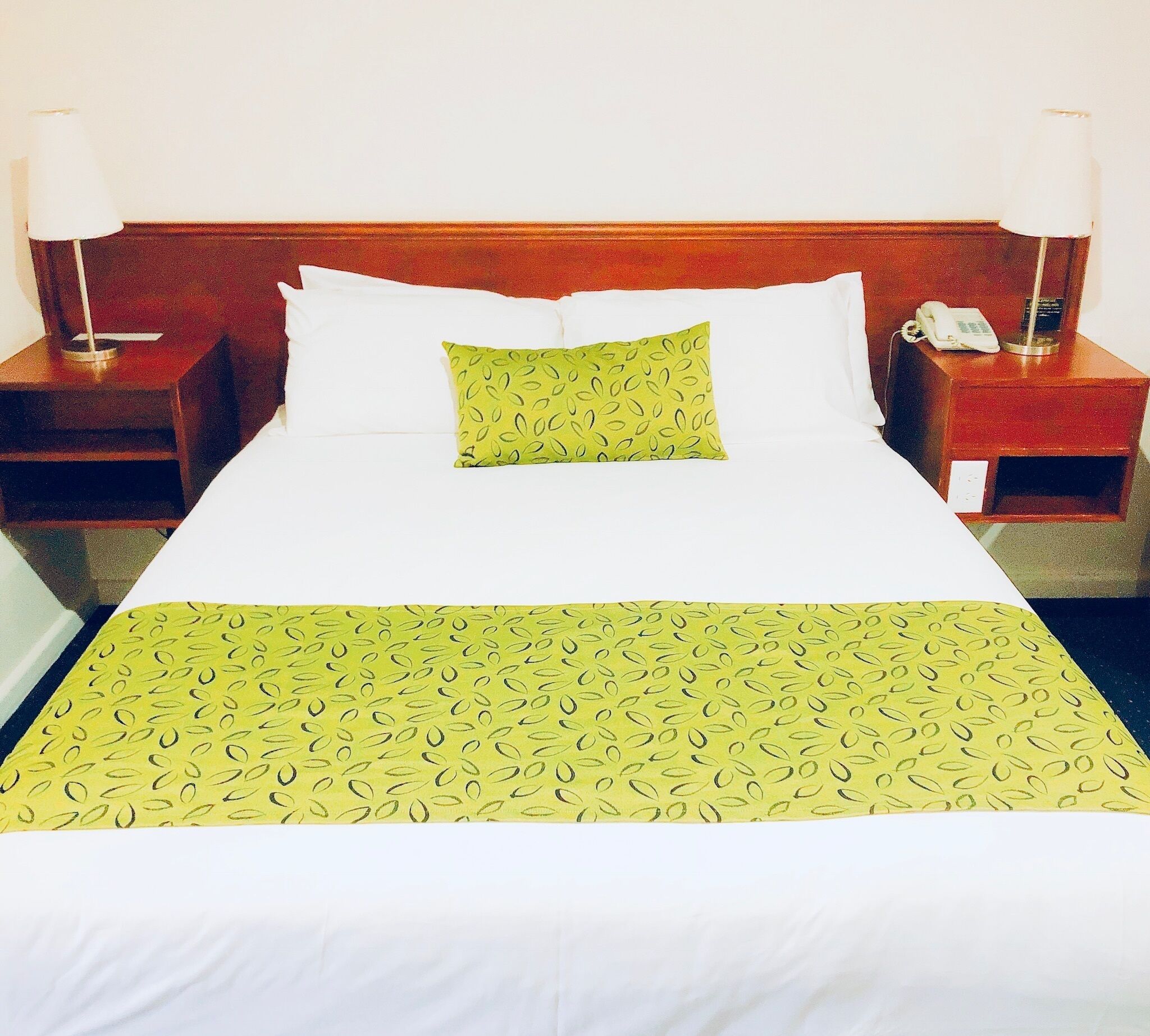 Une chambre d’hôtel avec un grand lit, deux tables de chevet, un téléphone et une lampe de chaque côté.