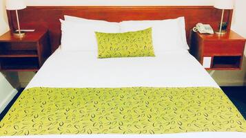 Une chambre d’hôtel avec un grand lit, deux tables de chevet, un téléphone et une lampe de chaque côté.