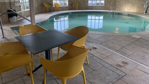 An indoor swimming pool with yellow chairs and tables, large windows, and safety signs. - La Quinta Inn & Suites by Wyndham OKC North - Quail Springs (Oklahoma City)