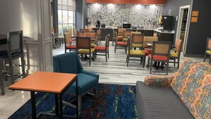A hotel lobby with a seating area featuring a mix of chairs and a sofa, a small table, and a patterned carpet. - La Quinta Inn & Suites by Wyndham OKC North - Quail Springs (Oklahoma City)