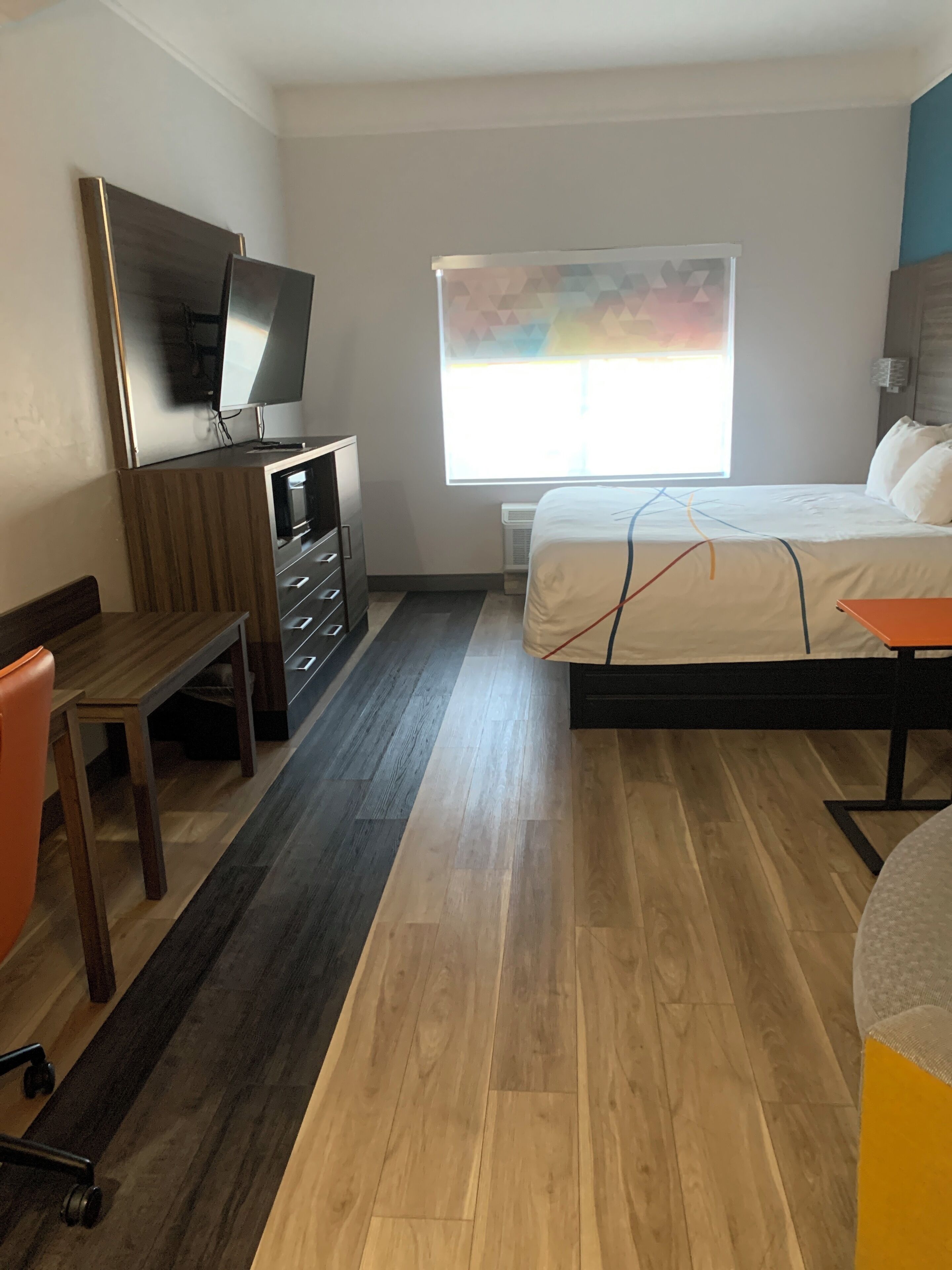 Habitación de hotel con cama, escritorio, silla, televisor y ventana con vistas.