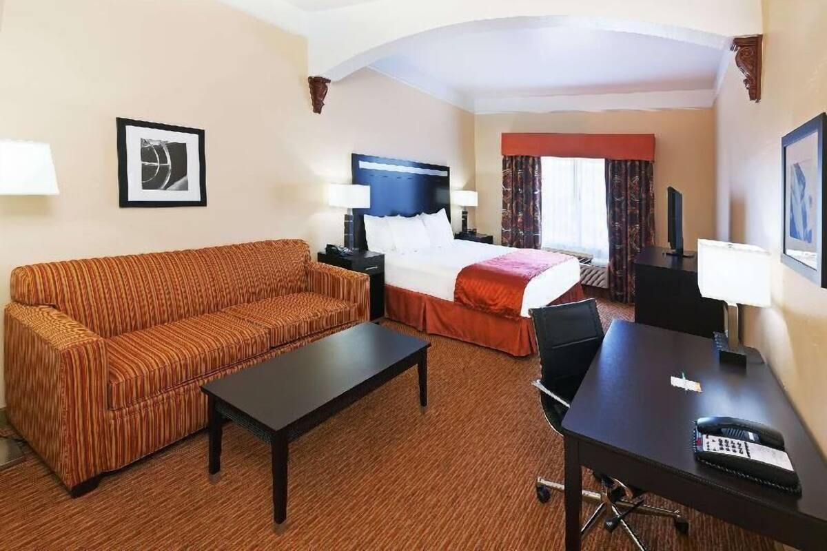 A hotel room with a bed, a sofa, a desk, and a chair.