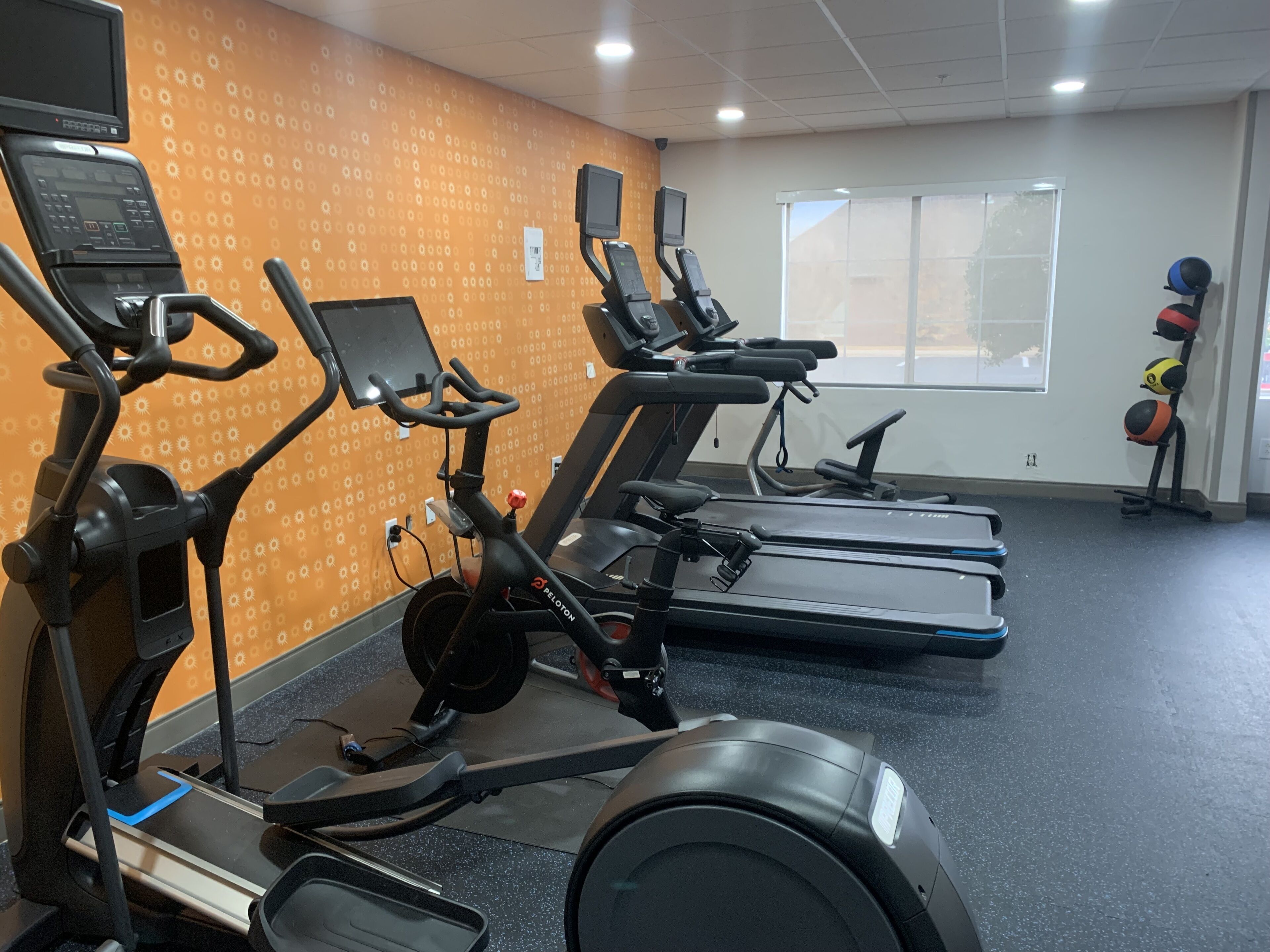 Un gimnasio con cintas de correr, bicicletas estáticas y una máquina de remo.