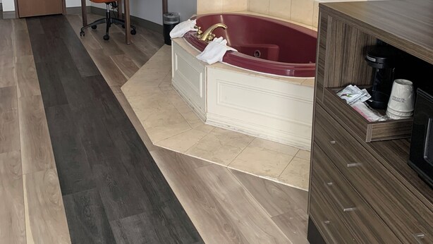 A modern bathroom with a freestanding bathtub, a wooden vanity, a desk with a chair, and a framed flower painting on the wall. - La Quinta Inn & Suites by Wyndham OKC North - Quail Springs (Oklahoma City)