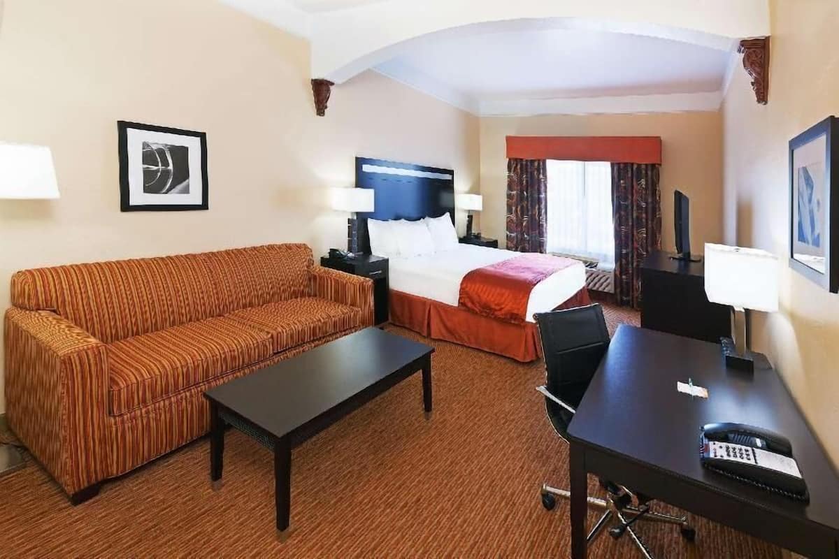 A hotel room with a bed, a sofa, a desk, and a chair.