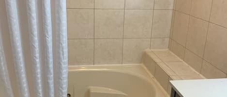 A bathroom with a bathtub, a shower curtain, and a sink.