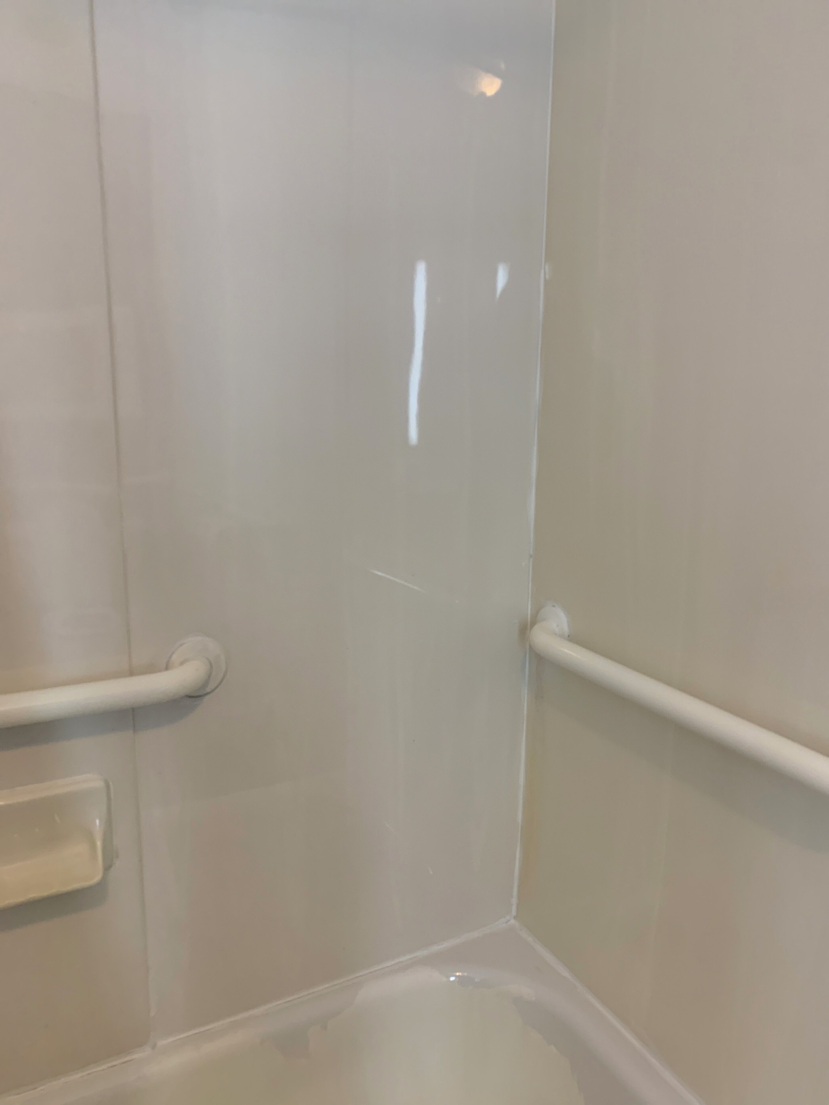 A corner of a room with a white bathtub, a white door, and a white handrail.