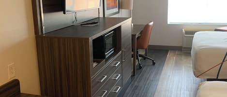 A hotel room with a bed, a desk, a TV, and a chair.