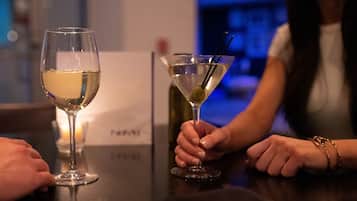 Two glasses of white wine on a table with a candle in the background.