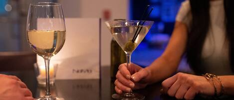 Two glasses of white wine on a table with a candle in the background.