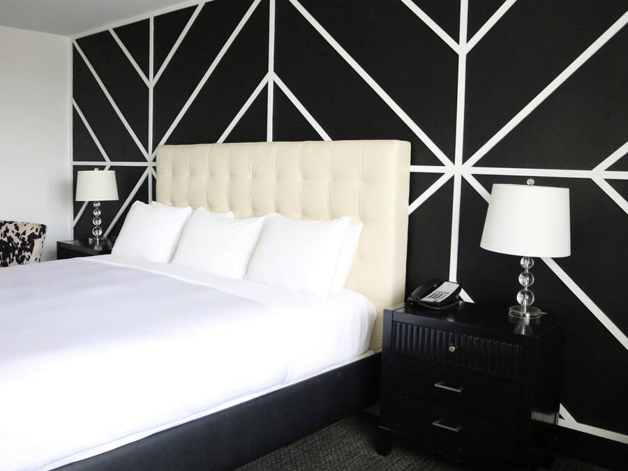 Una cama bien hecha con ropa de cama blanca, un cabecero capitonado y dos mesitas de noche con lámparas.
