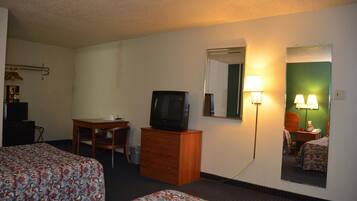 A hotel room with two beds, a desk with a television, a dresser, and a mirror.