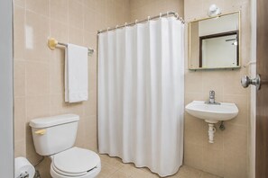 Un baño con inodoro, lavamanos, cortina de ducha y espejo.