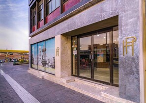 A hotel entrance with a large glass facade, a prominent 'R' logo, and a mural depicting a historical building. - Hotel Premier (Saltillo)