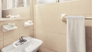 A bathroom with a sink, mirror, towel rack, and toiletries. - Hotel Premier (Saltillo)