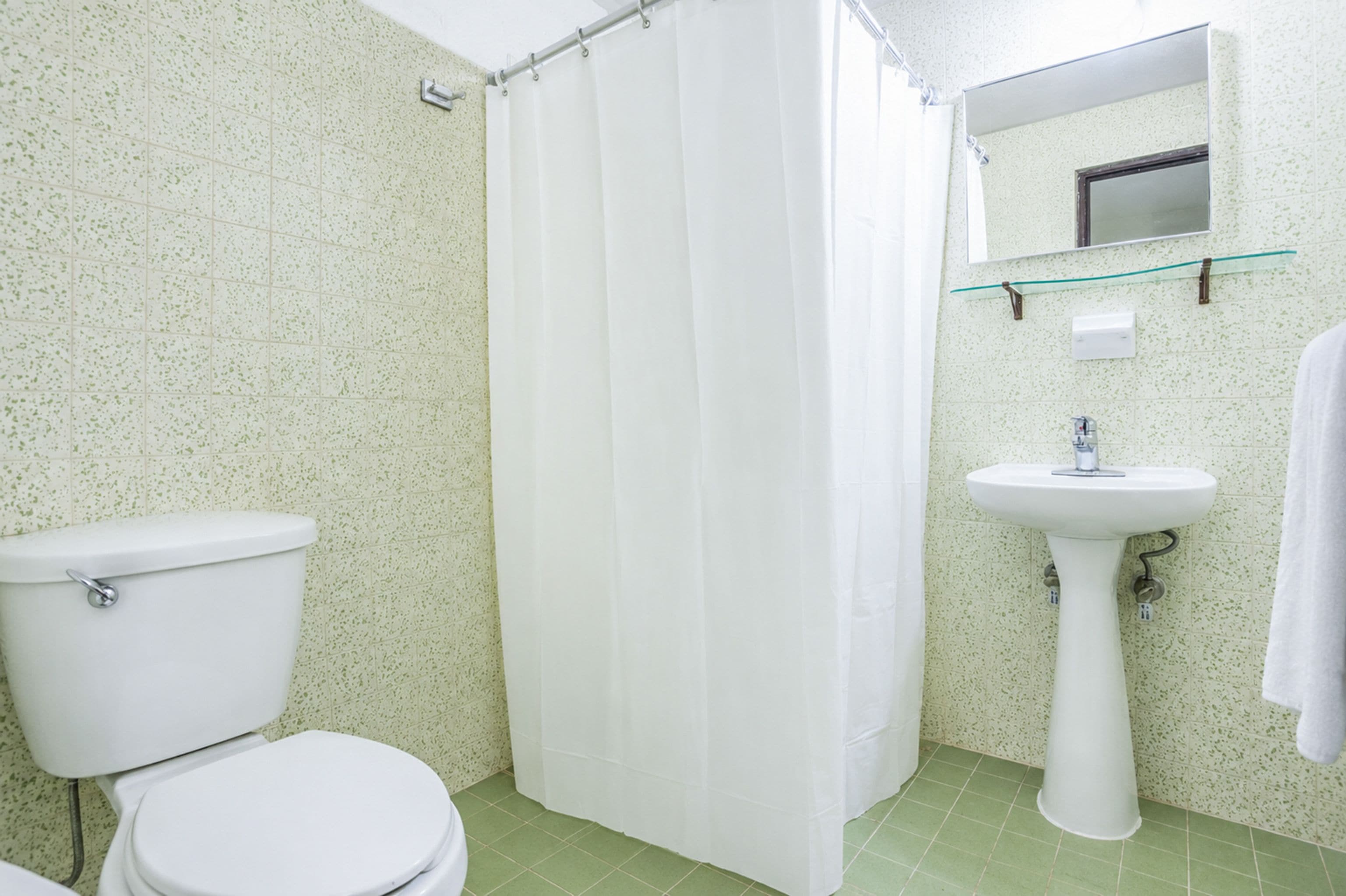 Un baño con inodoro, cortina de ducha, lavamanos y espejo.