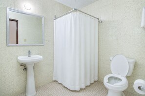 A bathroom with a white sink, a toilet, a shower curtain, and a mirror. - Hotel Premier (Saltillo)