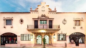 Un edificio de dos pisos con un balcón central, arcos en las entradas y detalles decorativos.