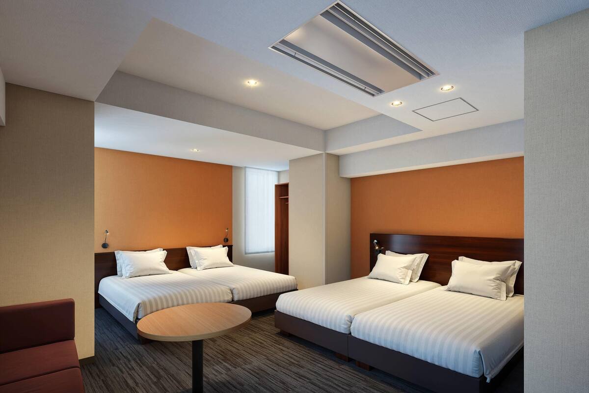 A hotel room with two beds, a round table, and a sofa.