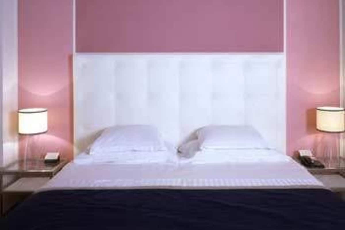 Una habitación de hotel con una cama grande, dos mesitas de noche y un cabecero.